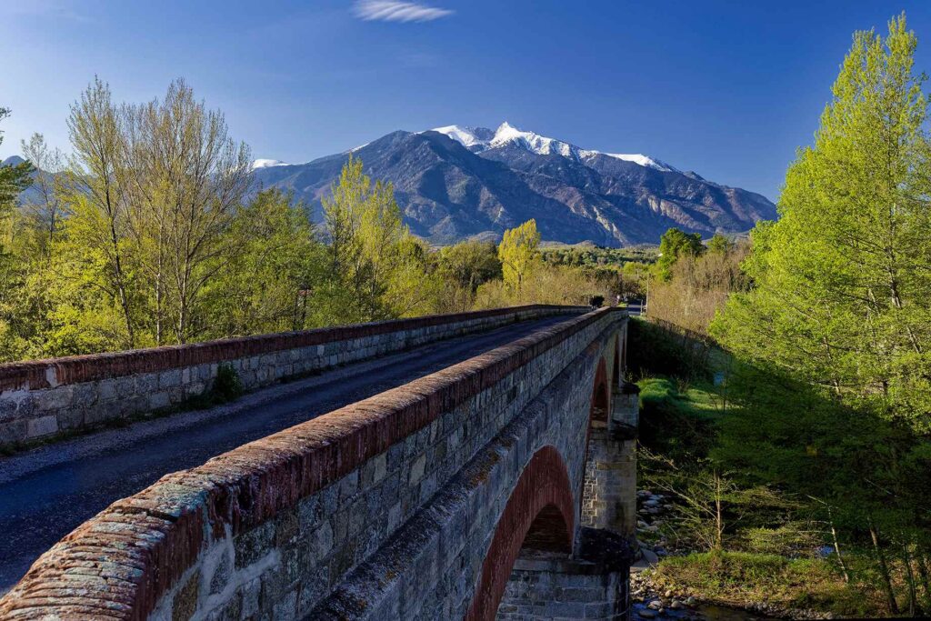 le pont conduisant à Eus avec au fond le Canigou enneigé au début du printemps