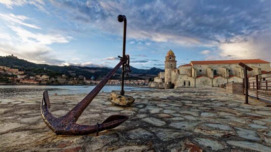 une ancre en premier plan devant la baie de Collioure et son église